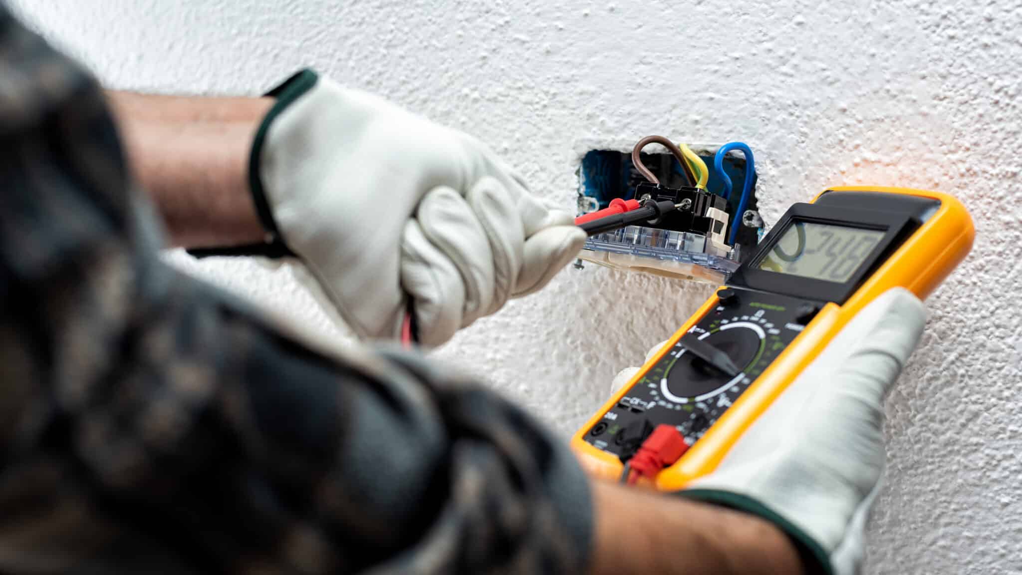 An electrician at work, using a tester to measure the voltage in an electrical system, including checking for reverse polarity.