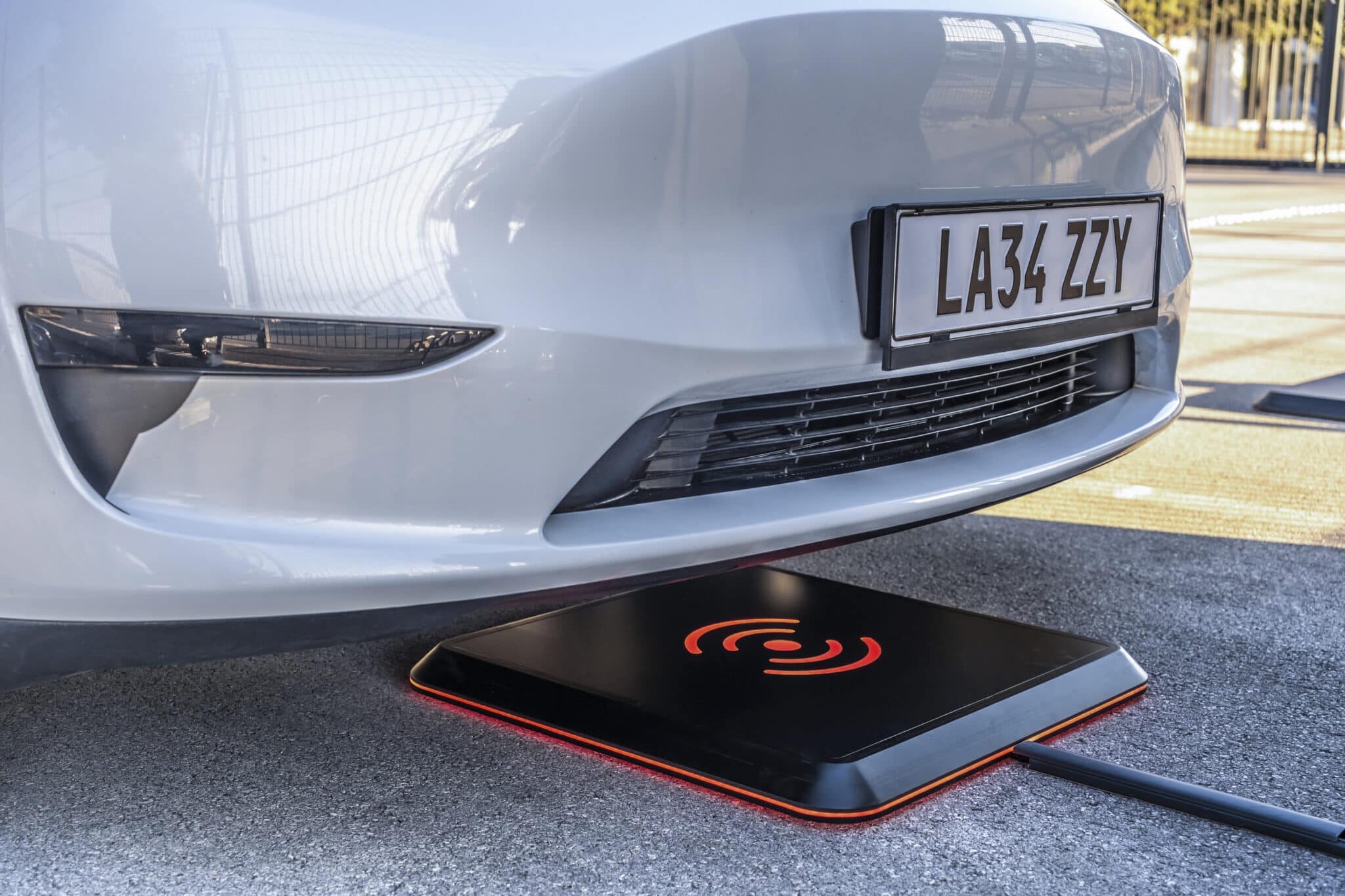 Electric car being charged with wireless charging under the car's bonnet.